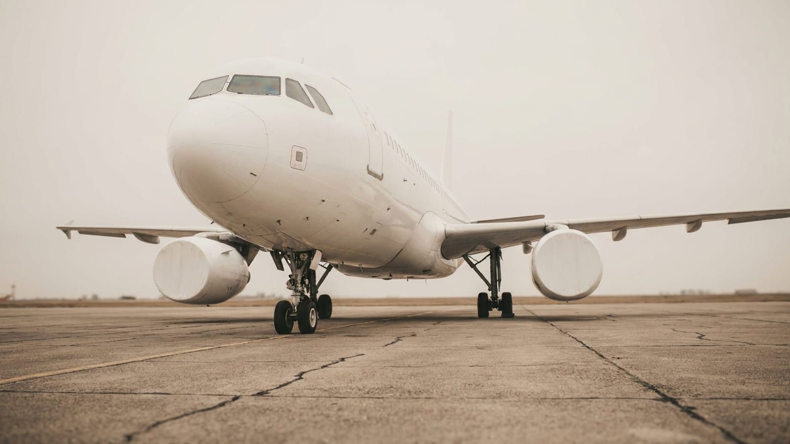 Weißes Verkehrsflugzeug schräg von vorn, die Triebwerke dicht über dem Boden